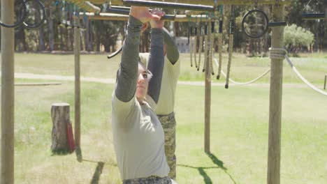 diverse male and female soldier hanging on trapeze bars at army style obstacle course in the sun