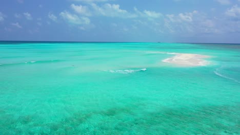 paradise scenery of calm clear water on turquoise color around a tiny white sandy pile under bright cloudy sky in maldives