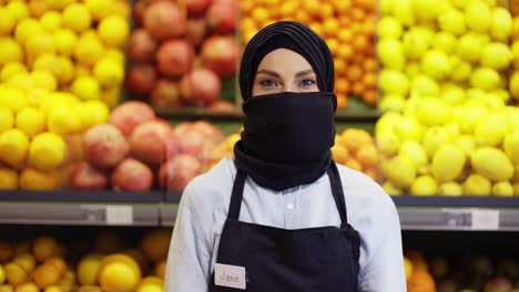 Portrait-of-supermarket-female-muslim-worker-standing-with-fruit-department-on-background