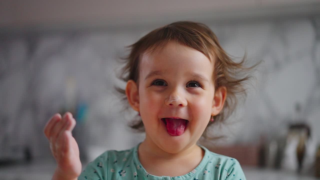Un vivace bambino con capelli sbarazzini e un sorriso smagliante, immortalato in un momento divertente a casa, che esprime felicità e curiosità in un ambiente allegro