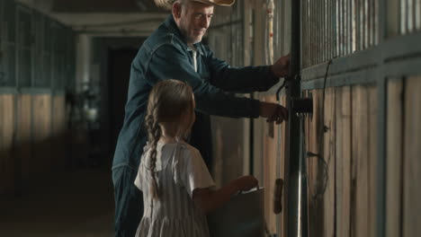 grandfather and granddaughter in a stable