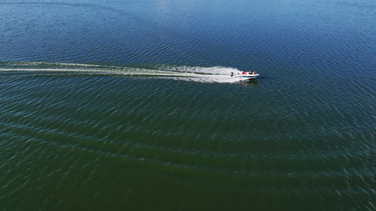 Motorboat on blue water surface. Tourists travel in a high-speed boat in the sea. White foam after the boat sailing on water. Aerial view.