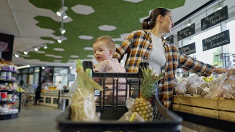 Ein-Glückliches-Brünettes-Mädchen-In-Einem-Karierten-Hemd-Geht-Zusammen-Mit-Ihrer-Kleinen-Tochter-Durch-Den-Laden-Und-Wählt-Beim-Einkaufen-Im-Supermarkt-Waren-Aus