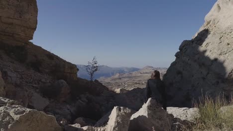 vista aérea hacia atrás de la montaña akoura en un día soleado con una chica pensativa
