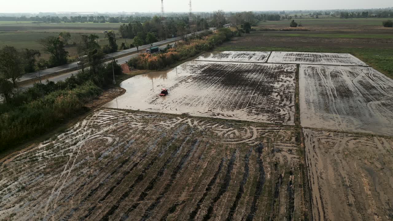Pemandangan udara sebuah traktor kecil membajak sawah berlumpur