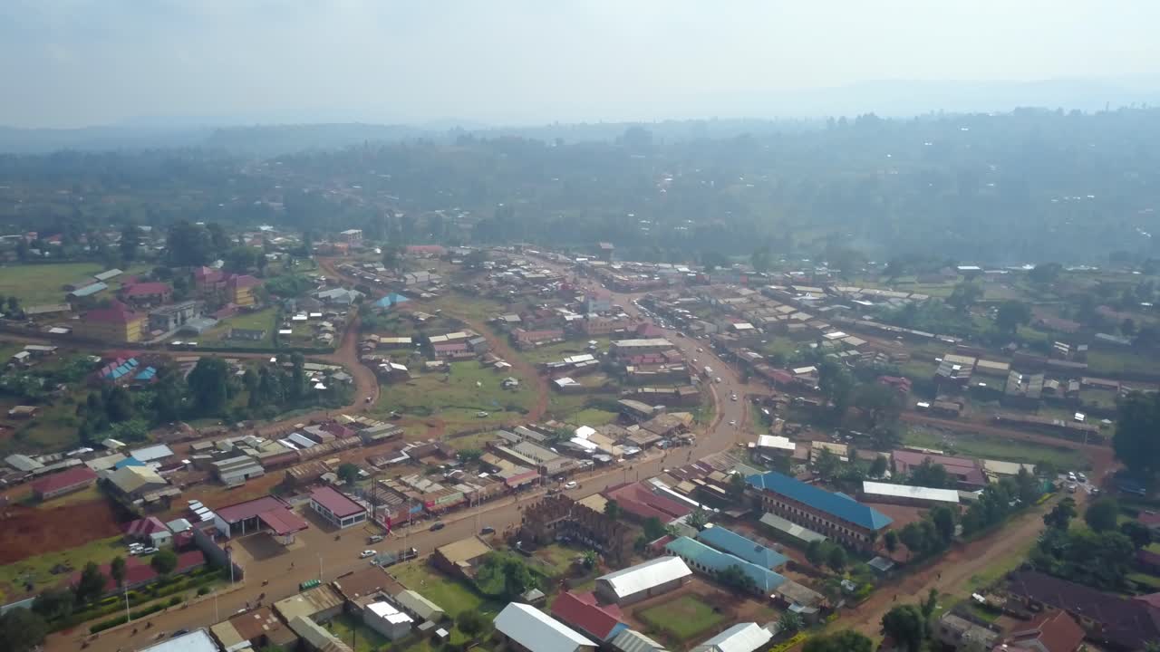 Drone pullout over Kapchorwa Town in Eastern Uganda showing the B1 road, Kapchorwa District HQ, Kapchorwa Modern Market, schools and churches with hills and haze in background.