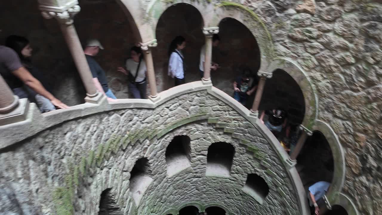 Visitors explore the spiral staircase at Quinta da Regaleira in Sintra, Portugal, a famous landmark