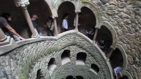 visitors explore the spiral staircase at quinta da regaleira in sintra, portugal, a famous landmark