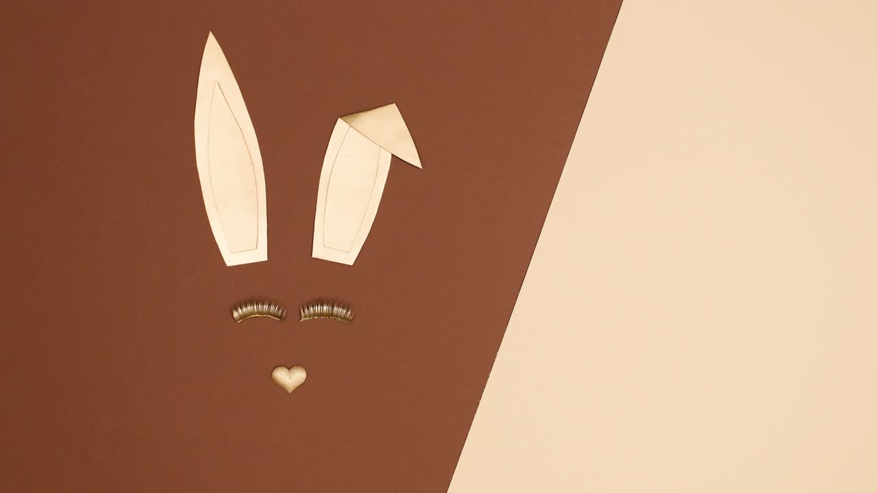Creative Golden Easter bunny blinking with eye lashes on nude brown background. Stop motion