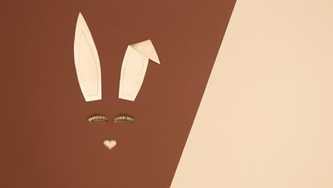 creative golden easter bunny blinking with eye lashes on nude brown background. stop motion