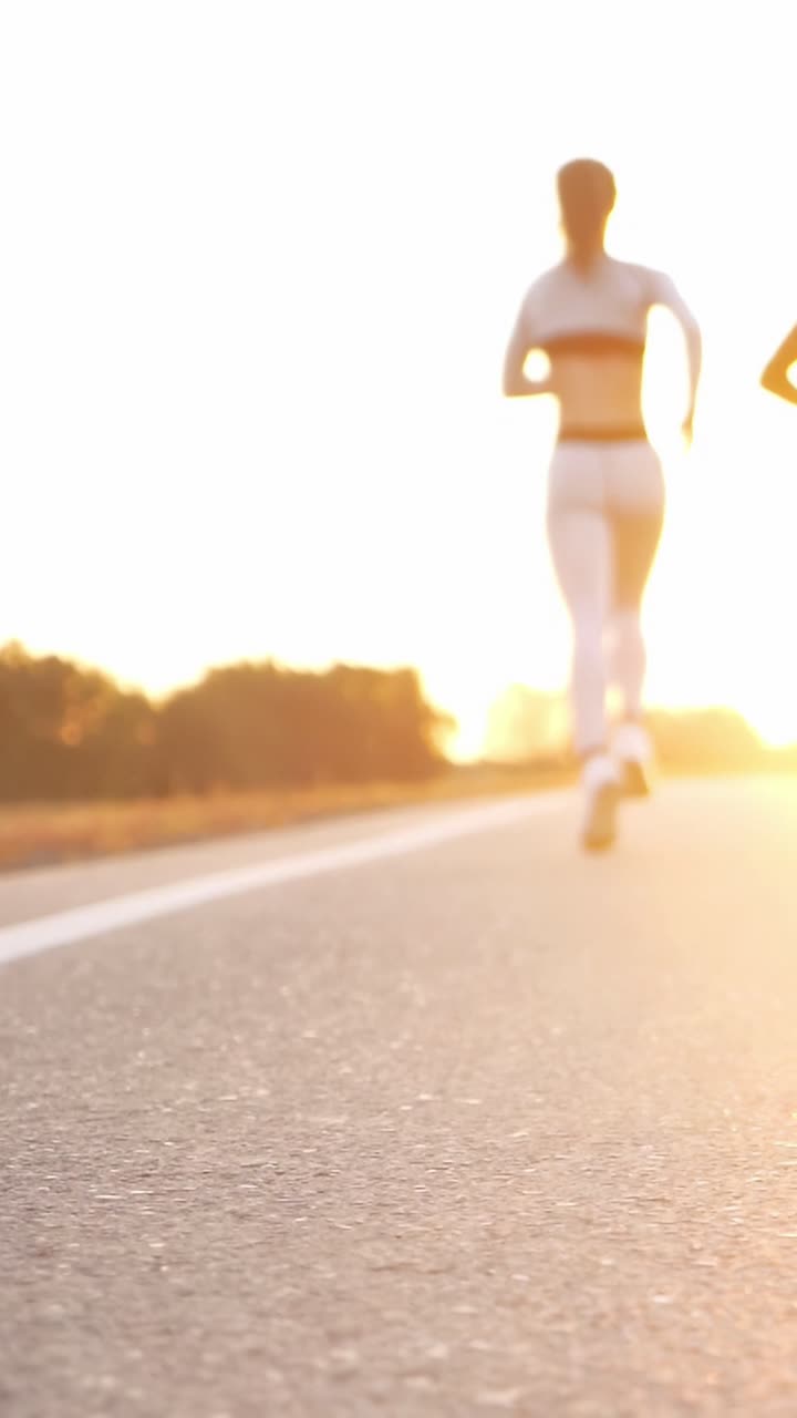 Athletic woman running on a sunlit road, showcasing fitness and determination in motion