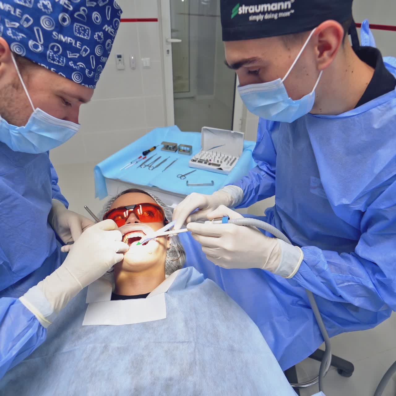 Top view of stomatology process in clinic. Dentists treating woman's teeth in a modern dental office.