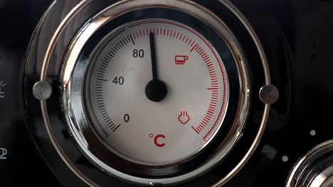 el dial de temperatura de la máquina de café rojo y negro se enfría lentamente en grados centígrados, electrodomésticos recién hechos, vaporizador de café caliente