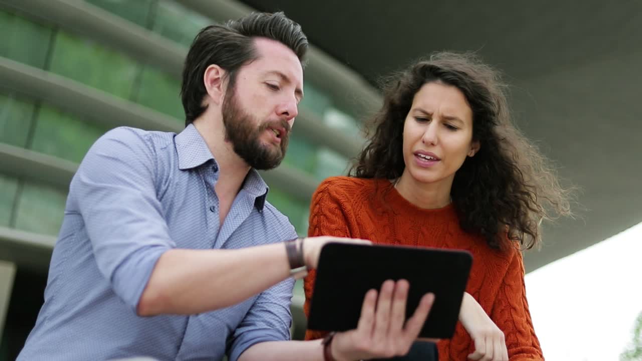 pareja enfocada usando una tableta digital al aire libre