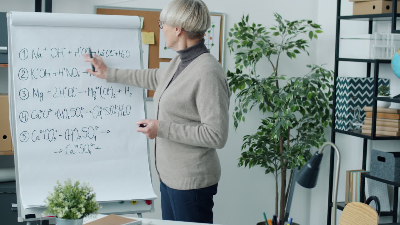 Chemistry Teacher Explaining Chemical Equations on a Whiteboard
