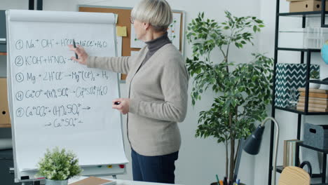 chemistry teacher explaining chemical equations on a whiteboard