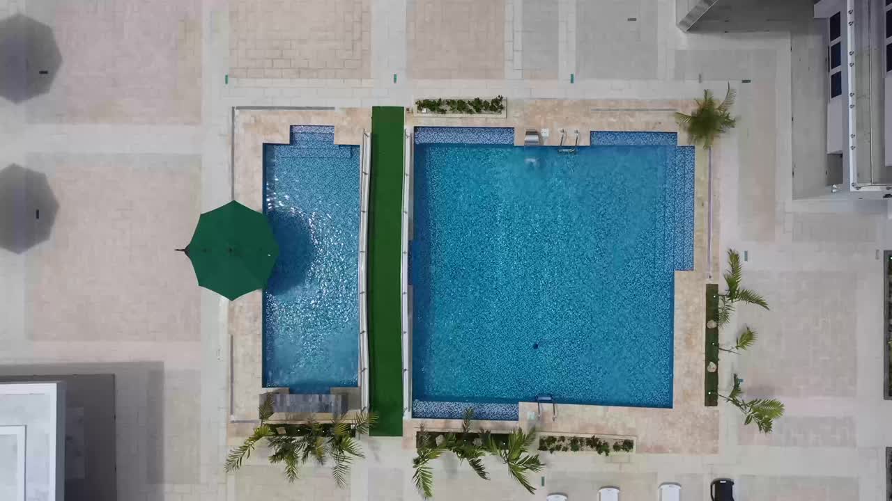 Dronebillede af smuk, blå swimmingpool i landvilla