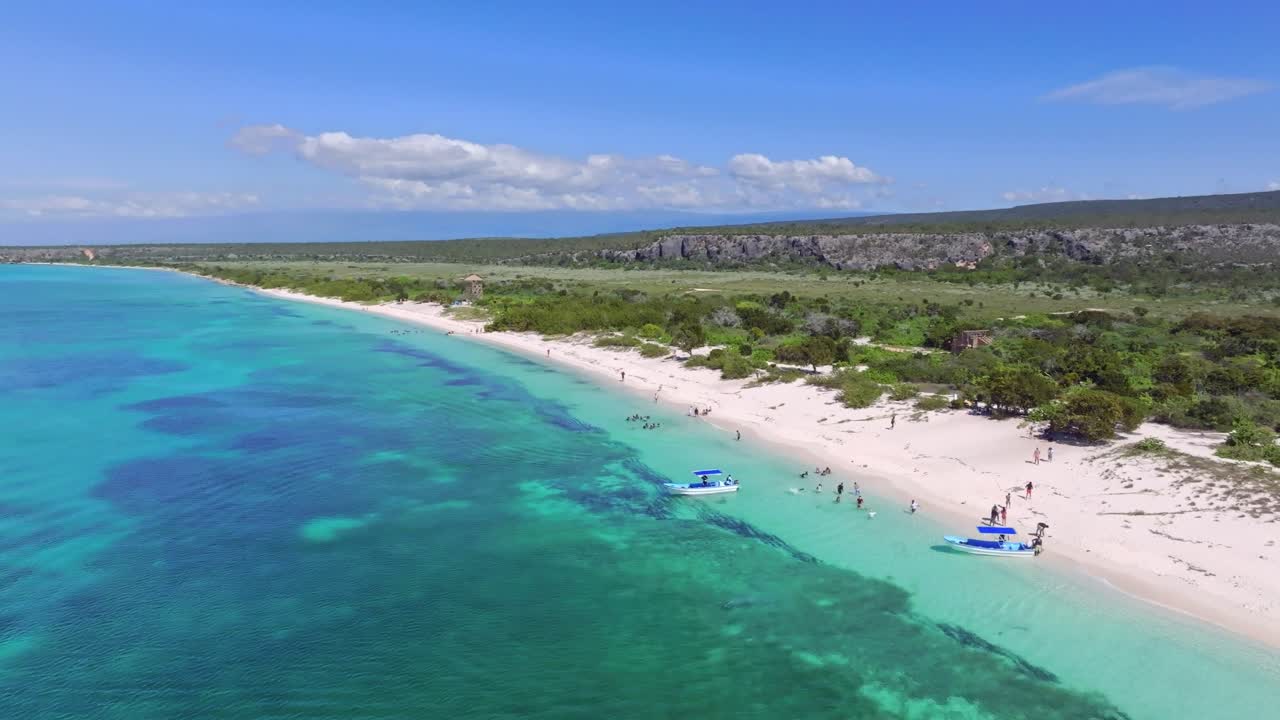 페데르날레스 (pedernales) 의 라스 아길라스 만에서 보트를 타고 있는 관광객을 보여주는 공중 사진, 파란 물과 모래 해변이 있는 아름다운 풍경