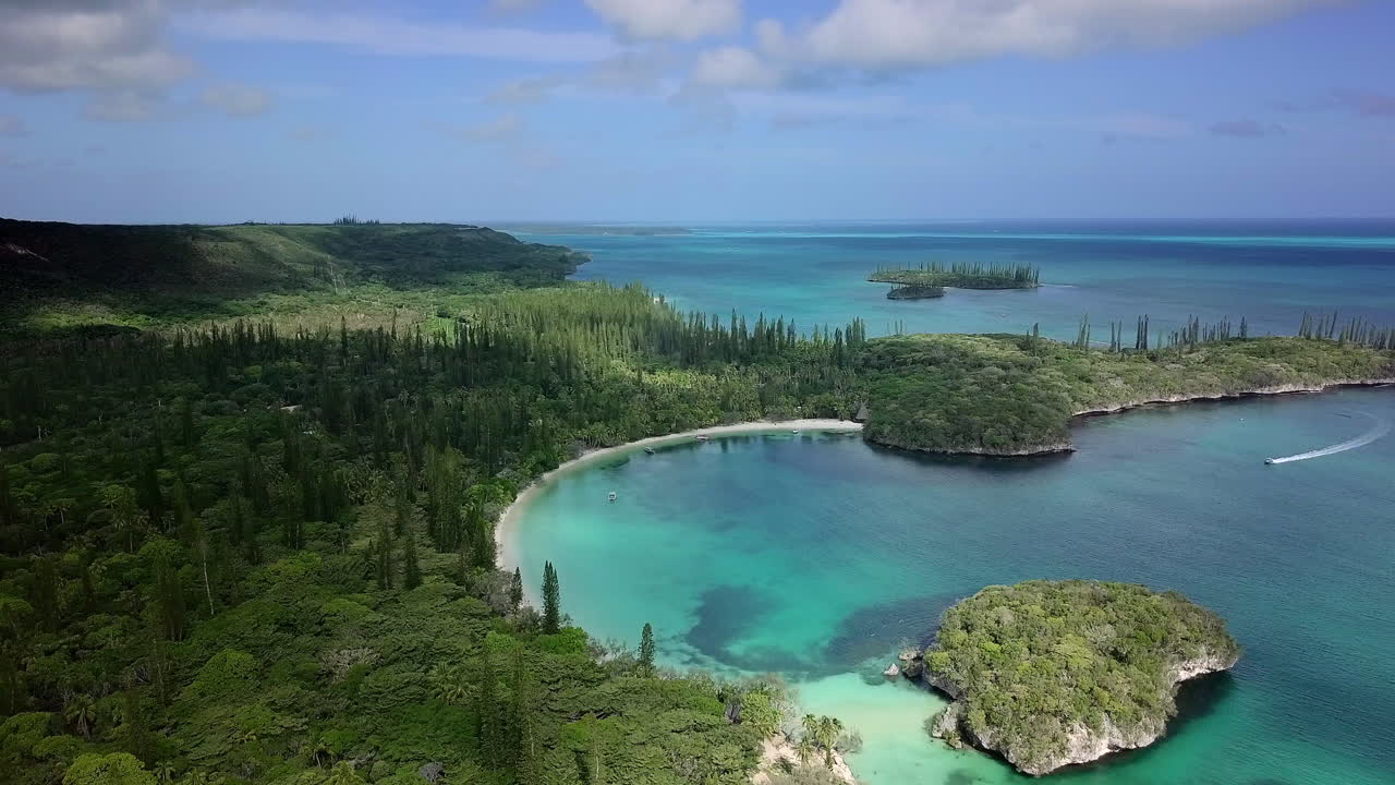 Ascending aerial over Kanumera bay and lush forest. New Caledonia