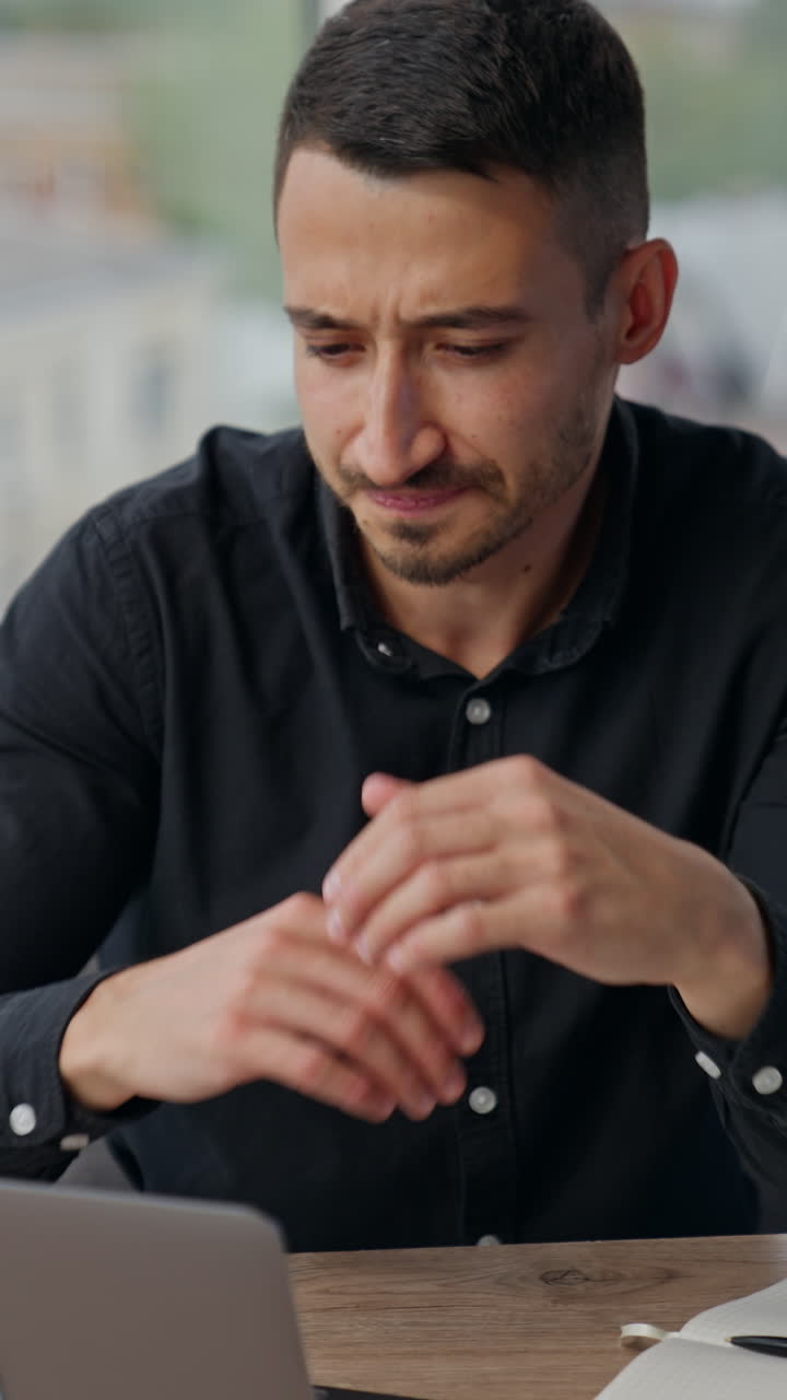 Man with concerned expression on his face looking at laptop. Busy man thinking over his problems at work, hard tasks or challenges. Vertical video