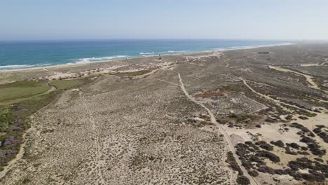 Culatra-island-in-portugal-showcasing-sandy-dunes,-green-patches,-and-the-atlantic-ocean,-aerial-view