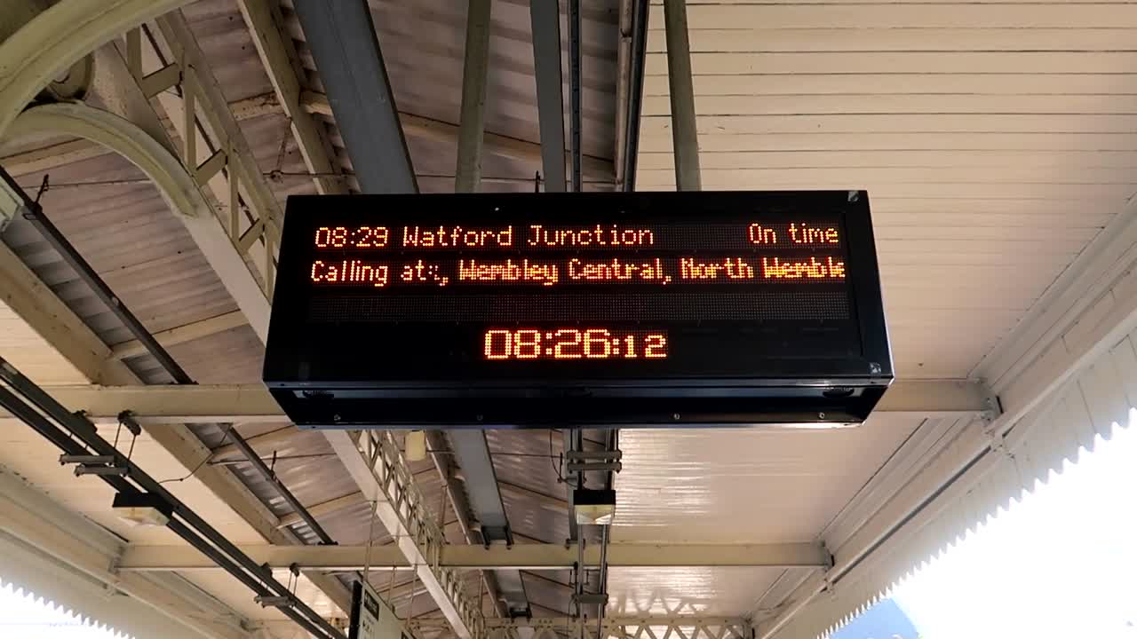 보드에 다른 정류장이 있는 왓포드 역에 접근하는 기차의 핸드헬드 샷