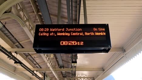 hand-held shot of a train approaching watford station with other stops on the board