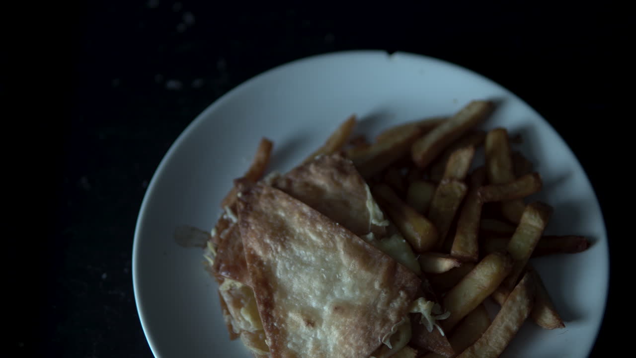 Nærbilde av nachos og pommes frites på hvit tallerken i svart disk