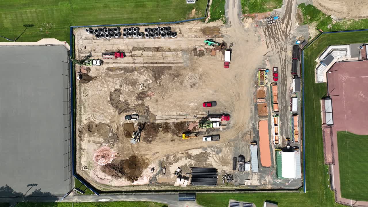 Top down aerial ascend of construction yard with vehicles, equipment, and structural layout in progress