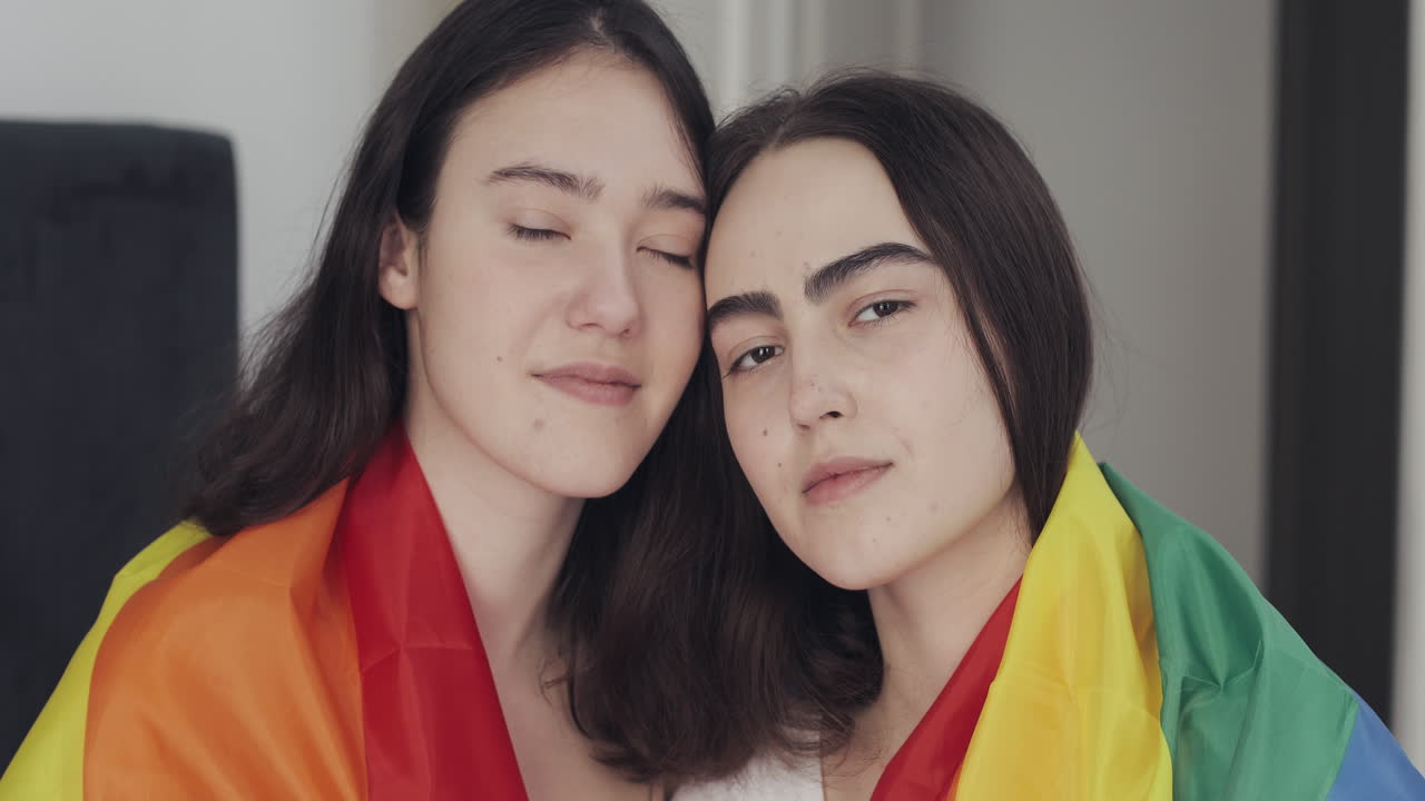 Two lesbian women posing with a pride flag