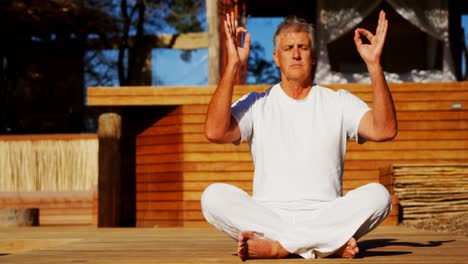 senior man meditating yoga on wooden plank 4k