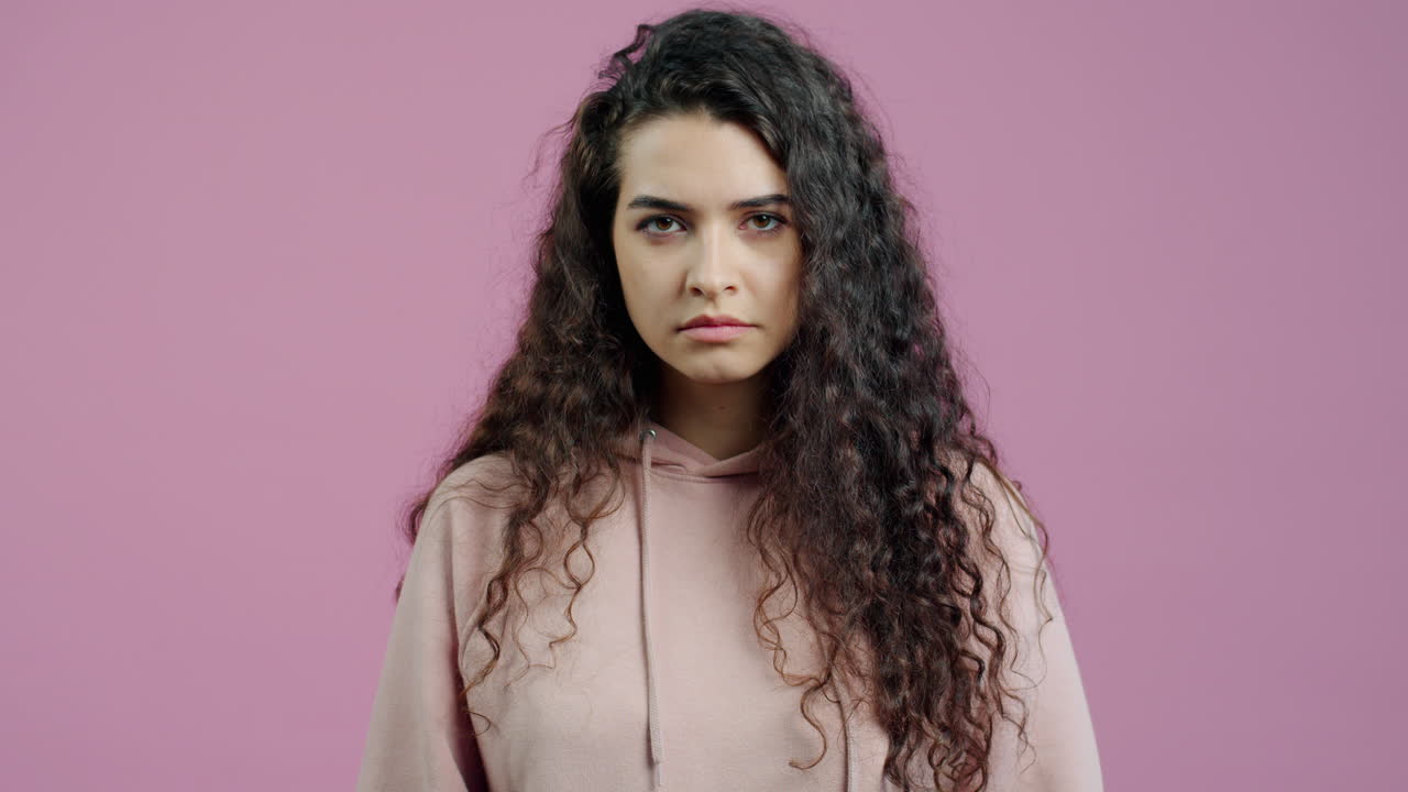 Woman with curly hair wearing a pink hoodie