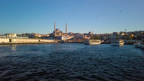 Vista-Desde-Un-Barco-Del-Puerto-De-Eminonu-En-El-Bósforo,-Estambul,-Turquía-Con-Una-Vista-De-Tren-De-Un-Tren-En-Primer-Plano-Y-Una-Mezquita-En-El-Fondo