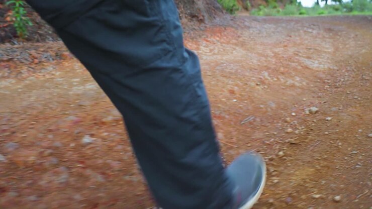 Piedi e gambe di un uomo che camminano nel bosco
