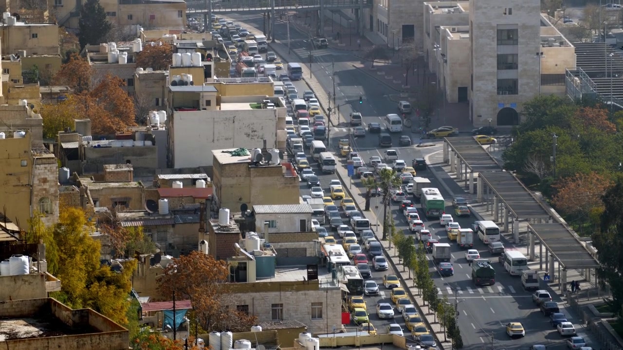 Veduta dall'alto della congestione del traffico urbano su un viale cittadino ad Amman al tramonto. Pendolari che guidano auto su una rete stradale autostradale affollata nella capitale della Giordania durante l'ora di punta al crepuscolo