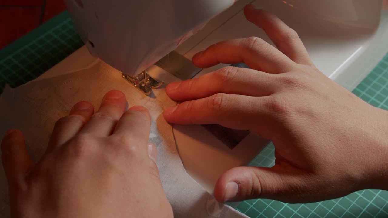 Slow motion of fabric being sewn with a sewing machine operated by a person