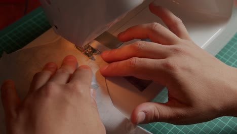 slow motion of fabric being sewn with a sewing machine operated by a person