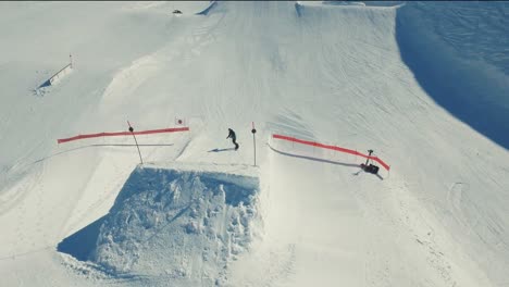 An-aerial-shot-of-a-snowboarder-going-over-a-large-kicker-and-doing-a-grab-in-the-snowpark-in-Avoriaz,-France