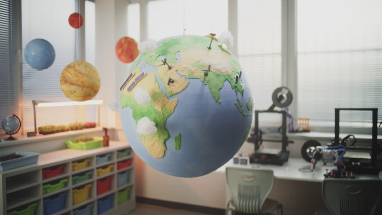 Globe with Miniature 3D Models of Wind Turbines and Solar Panels Hanging in Modern Classroom