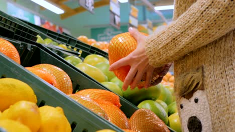 mujer comprando frutas cítricas exóticas frescas en la tienda de comestibles