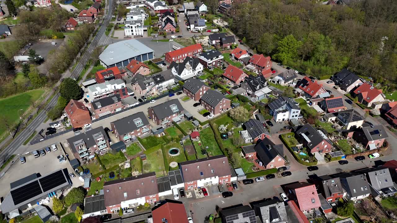 Suburb district with single Family houses and apartments in american city. Road with green trees in spring. Modern housing area with solar panel producing green energy. Aerial top down flyover.