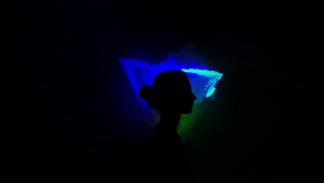 imagen de una niña en un fondo claro de diferentes colores moviéndose en la oscuridad. el humo llena el triángulo con la cabeza de la niña.
