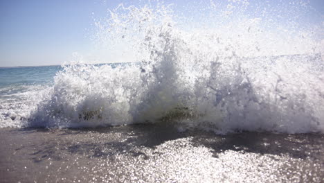 a wave crashes onto the shore, creating a dynamic spray of water with copy space