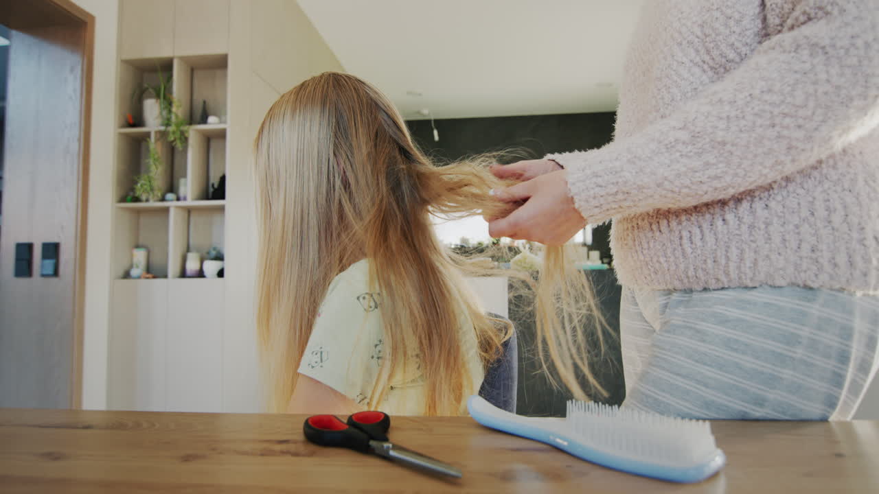 Mom untangles her daughter's long hair. Hair is very tangled and hard to comb