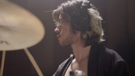 young male drummer in trendy shirt playing drums