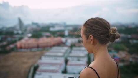 portrait shot of young woman standing on rooftop with a to go cup