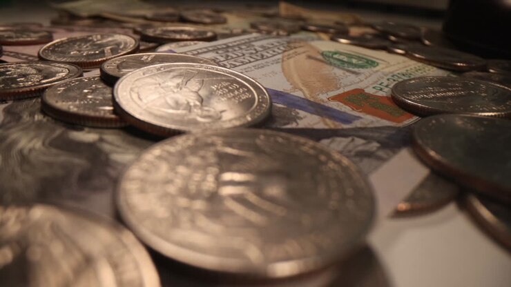 Monete e dollari cadono su un tavolo, primo piano.