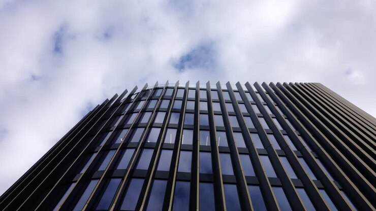 Edificio futuristico con facciata dorata e finestre scure durante una giornata nuvolosa, Praga