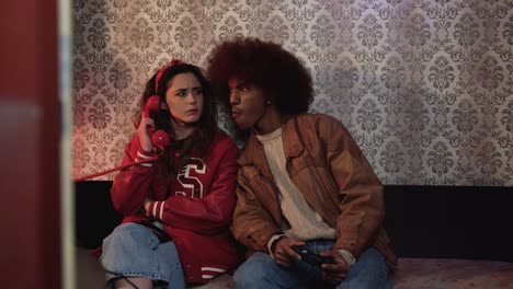 Woman-holding-retro-phone-receiver-while-sitting-with-black-boyfriend-on-sofa