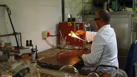 Side-view-of-mature-male-worker-blowing-glass-in-glass-factory-4k